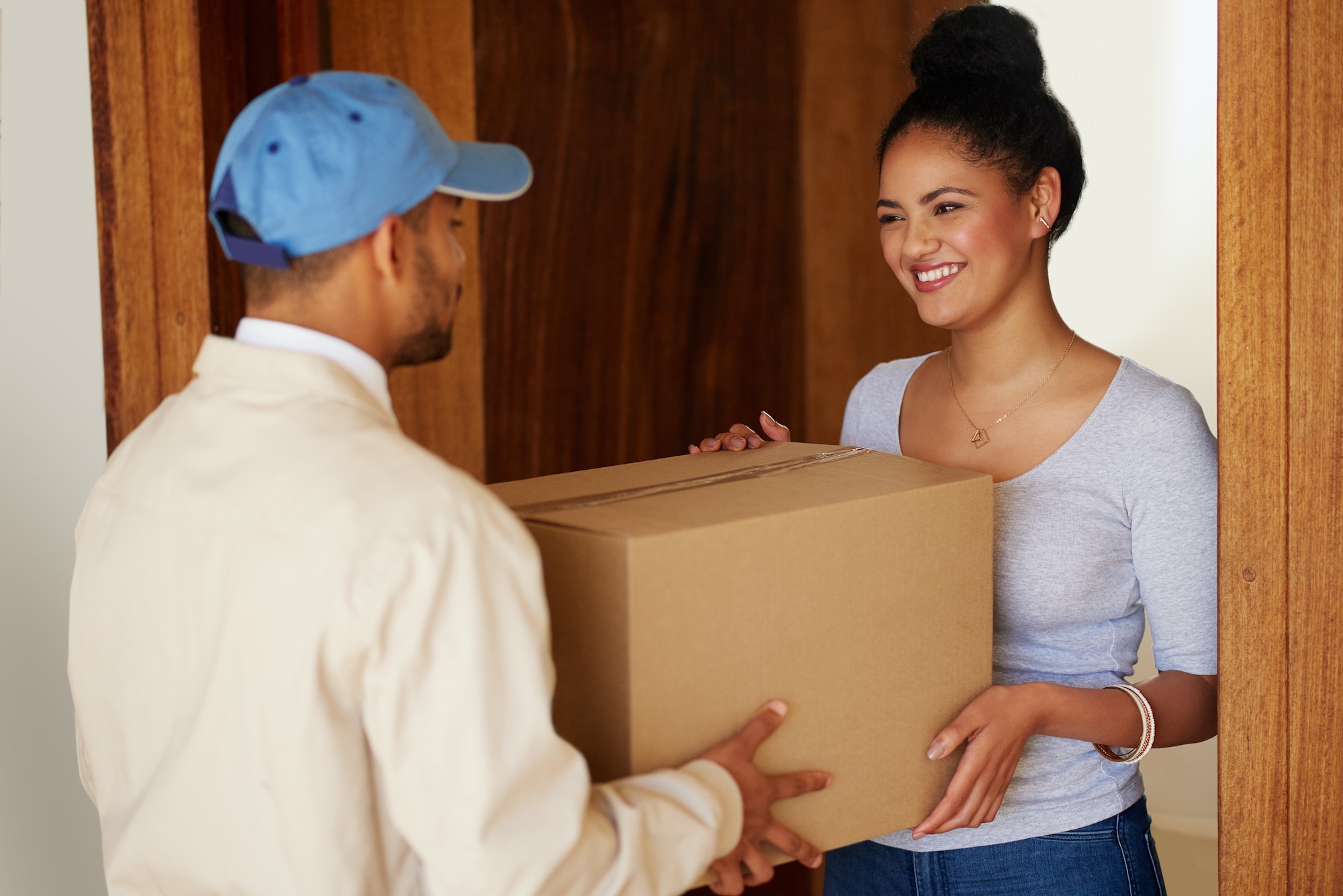 Shot of a delivery man making a delivery to a customer at her home